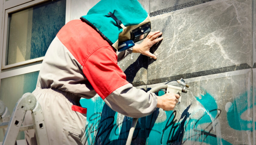 Worker Removing Graffiti from Building Surface